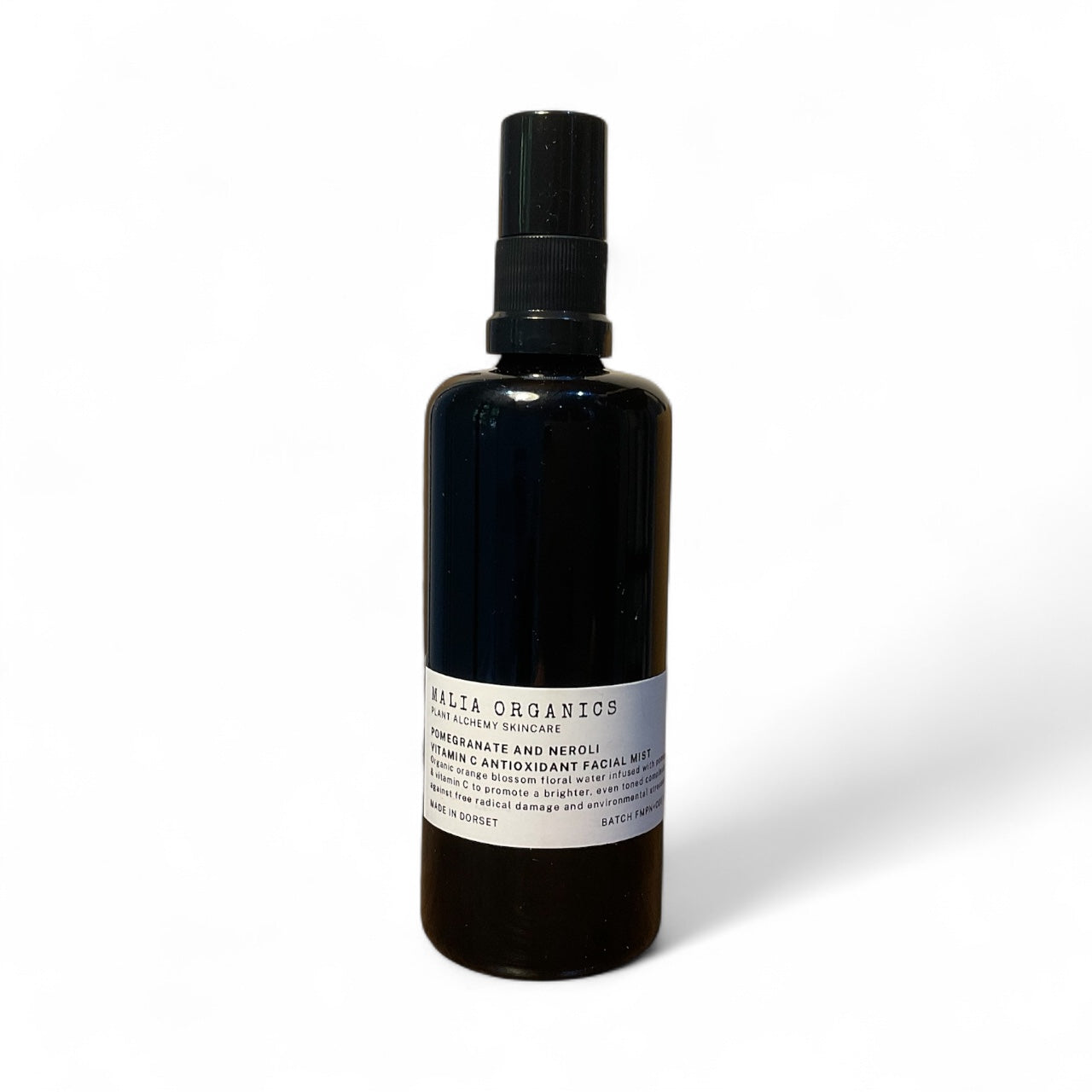 Black bottle with a label on a white background malia pomegranate and neroli facial mist