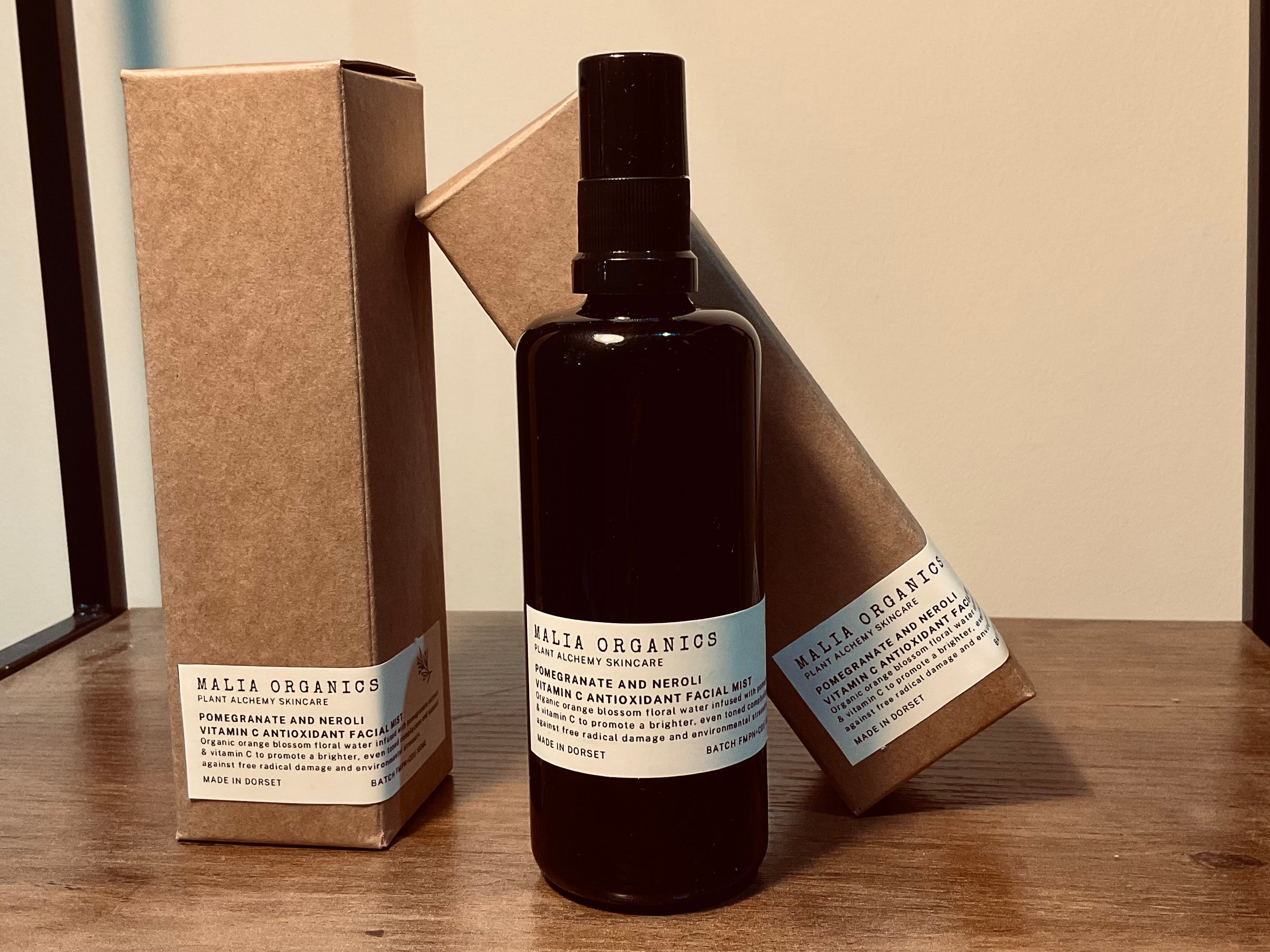 Black bottle with a label and brown box on a wooden surface facial mist